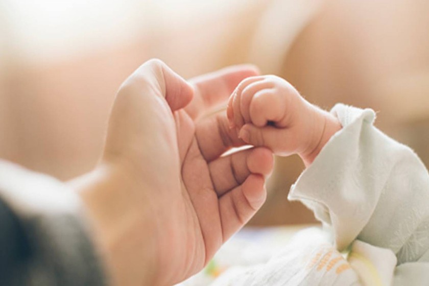 Ръка на майка,която държи бебешка ръчичка.