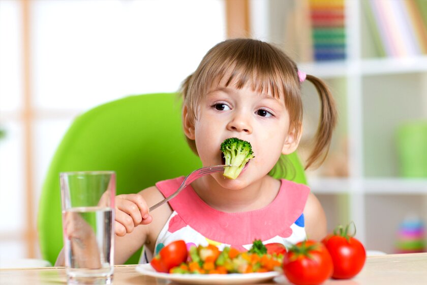 Дете яде зеленчуци.
